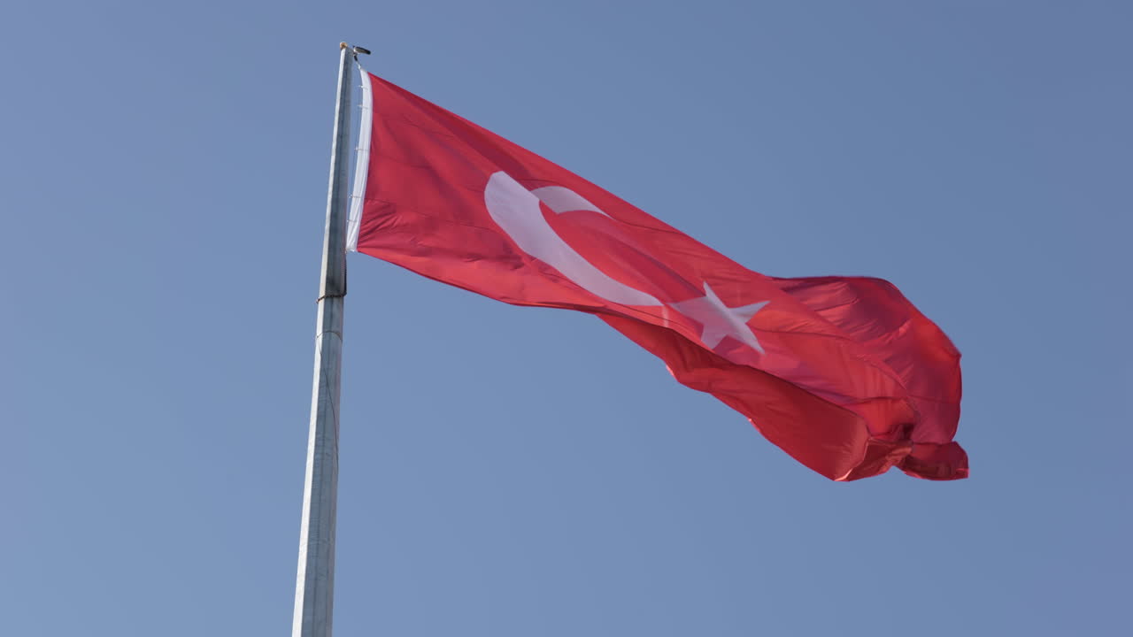 cámara lenta, bandera nacional de turquía ondeando en el poste bajo un cielo azul claro