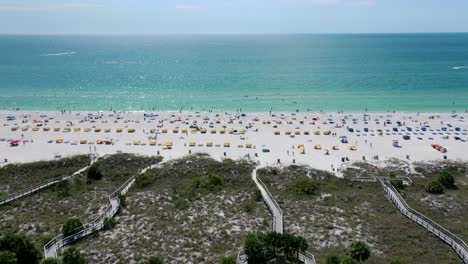 aerial view of people sunbathing and swimming at the beach on a hot summer day