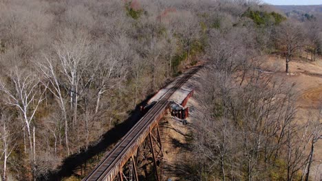 tight aerial shot of railroad tracks running out of the forest and on to the pope lick trestle in louisville kentucky