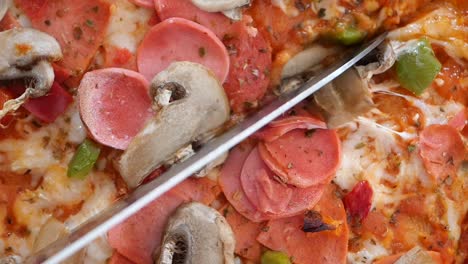 un primer plano de una deliciosa pizza siendo cortada con un cuchillo