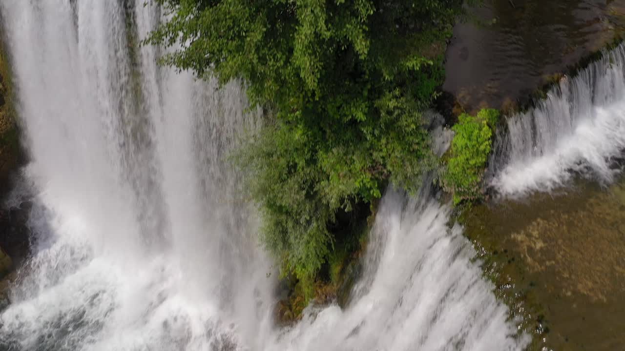 The Jajce Waterfall in Bosnia and Herzegovina with growing cliff tree at the end, Aerial flyover shot