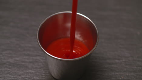 pouring ketchup into a stainless steel ramekin