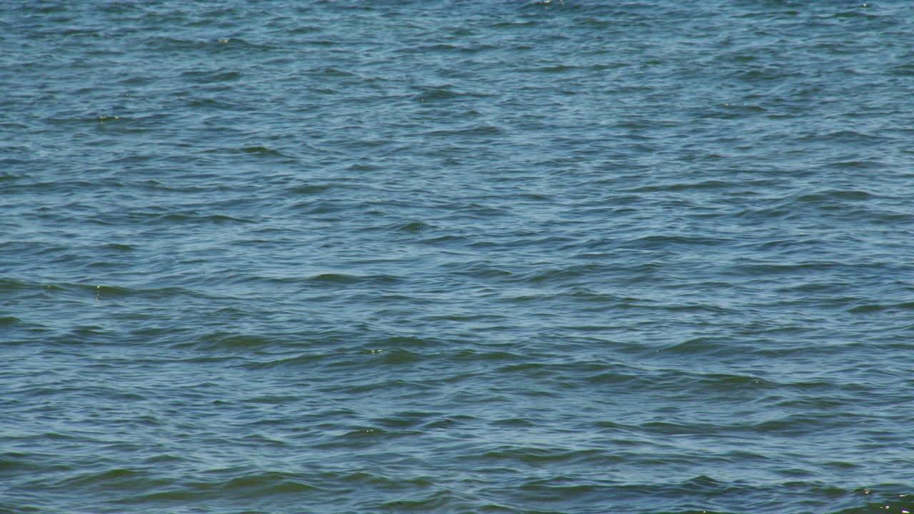 Mid shots of the see rippling in the sun at Cwmtydu beach