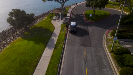 aerial orbit of person talking through car window on oceanside road