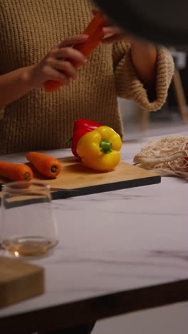 vertical video close up of woman getting home from food shopping unpacking and preparing bag of fresh vegetables onto counter in kitchen