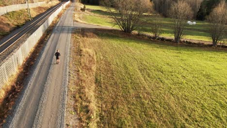 hombre corriendo por el camino de tierra del campo junto al campo verde cerca de ostersund, suecia