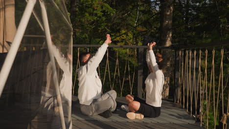 teacher demonstrates hand-raising asana to woman. people partake in mindfulness practices sharing moments of introspection and presence in each other company