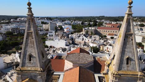 aerial drone shot fly back between two towers of a cathedral in alberobello, italy