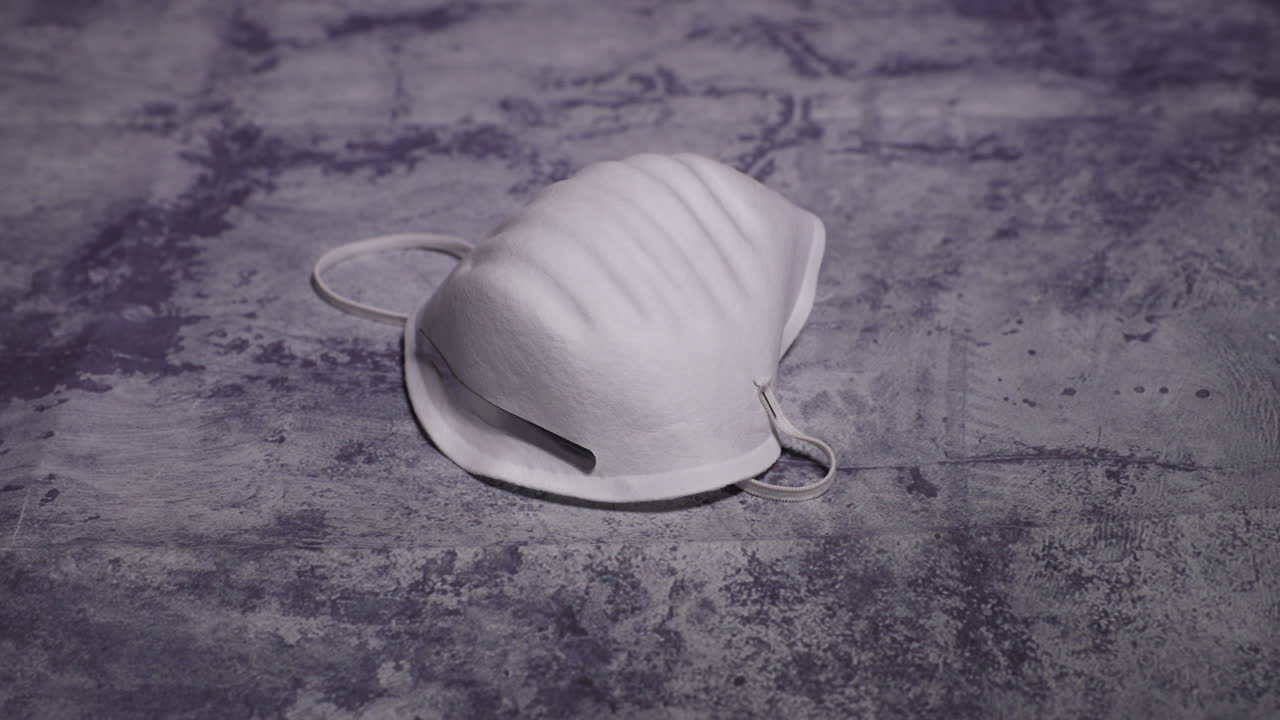 Men's Hand Lifting Protective White Mask Mask FFP2 Against Threats Like Corona Covid19 Virus Protects Mouth and Nose from Dark Black Board capture in 4k 60fps