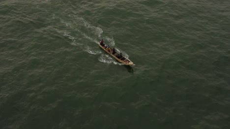aerial shot focused on a fishing boat, with one of the fishermen bailing water with a bucket