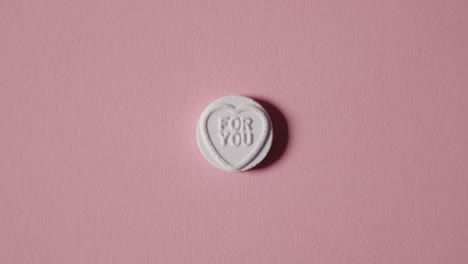 mano recogiendo caramelos de corazón con un mensaje para usted sobre fondo rosa