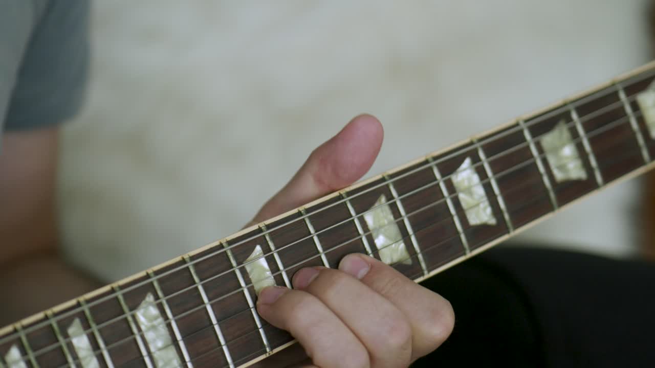 hombre tocando una guitarra eléctrica haciendo un solo con su mano izquierda en la cámara