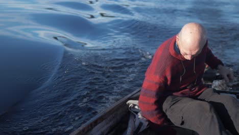 mature man bailing rowboat while driving