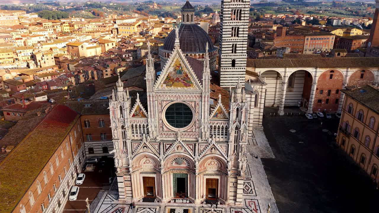 시에나 대성당의 화려한 고 양식의 전면과 토스카니아의 망기아 타워는 따뜻한 빛에 싸여 있습니다.