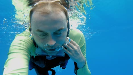 primer plano de la cara de un buceador sin máscara debajo de la superficie del mar