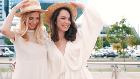 two happy friends laughing in straw hats