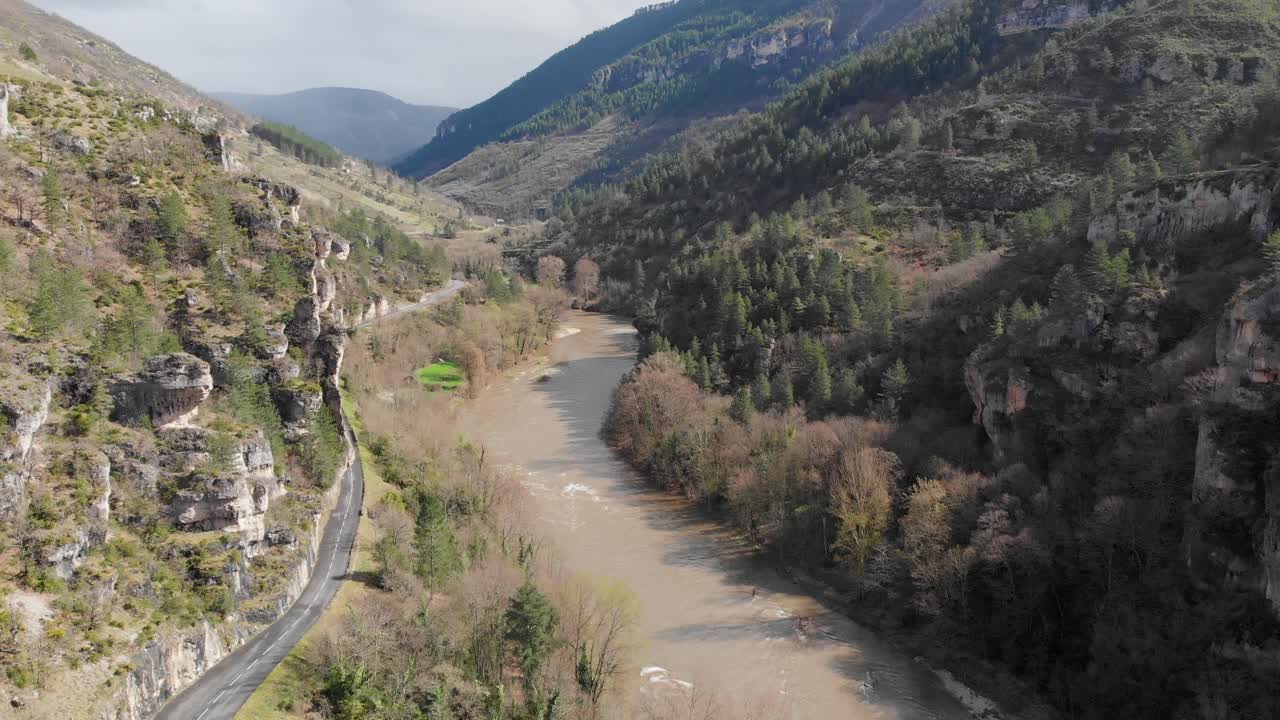 A river flowing through a deep mountain valley with a winding road alongside