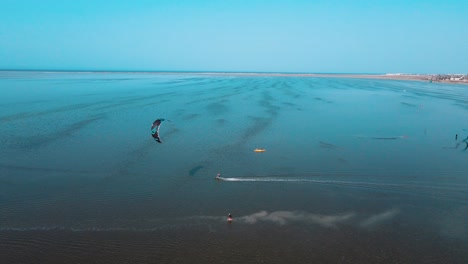 Una-Vista-Aérea-De-Un-Cuerpo-De-Agua-Con-Gente-Practicando-Windsurf-Y-Parasailing,-Kitesurf-En-El-Océano-De-La-Laguna-De-Djerba-En-Túnez.