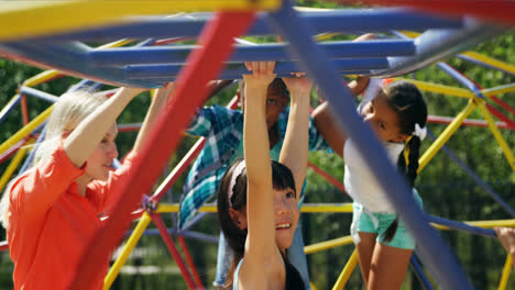 Trainer-assisting-schoolkids-while-playing-in-playground