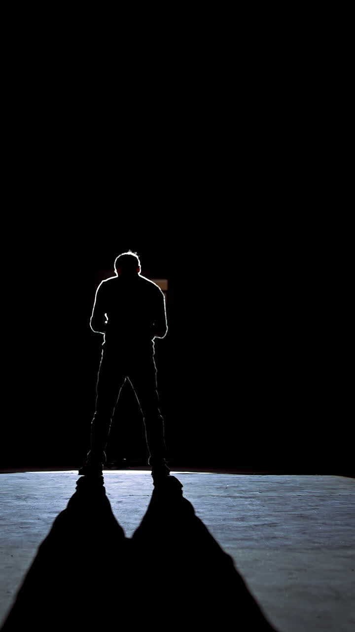 Senior man in costume on stage in darkness. Active man in hat dancing on stage during the performance in the theater. Vertical video