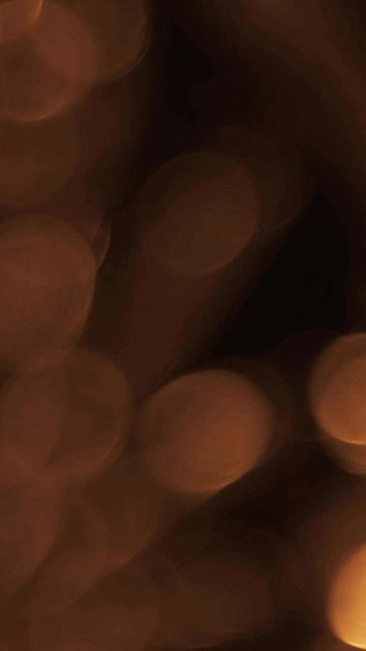 Particelle di Luce Bokeh Dorate Astratte Fluttuanti su Sfondo Scuro