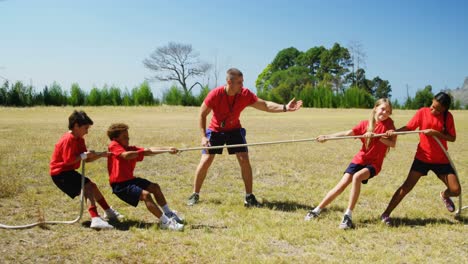 trainer assisting kids in tug of war during obstacle course training