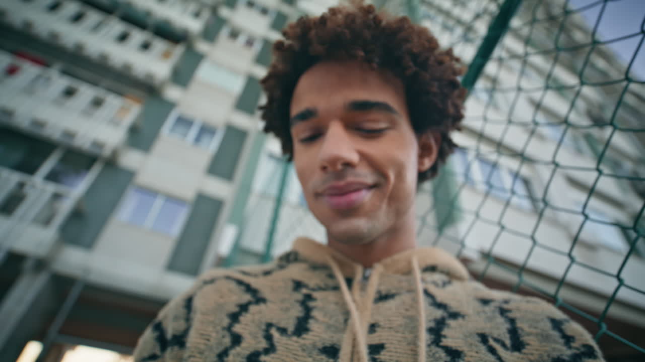 Mands hænder taster på smartphone-skærm på en aften gade, tæt på. Smilende latinamerikansk fyr.