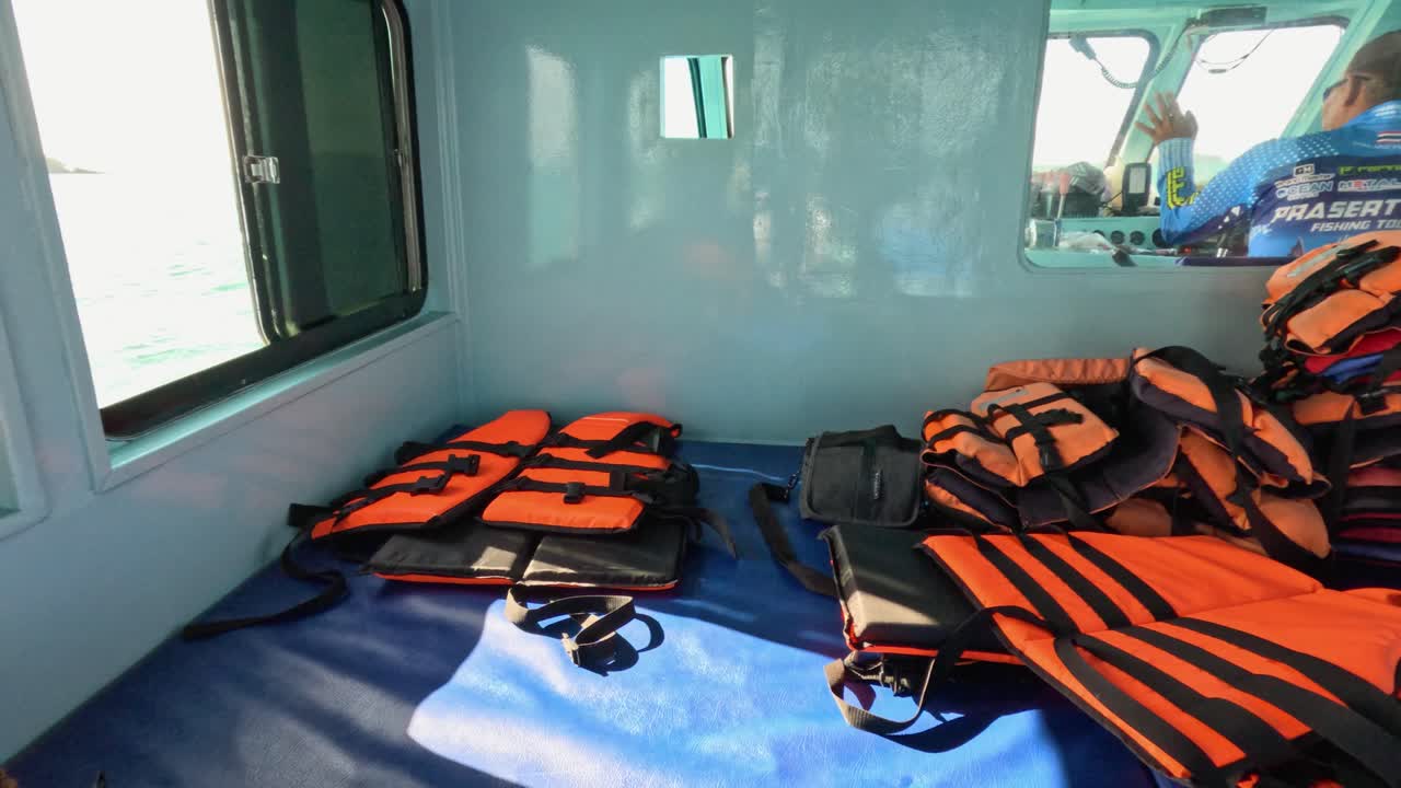 Bright orange life jackets inside a boat cabin with sunlight streaming through windows, creating a vibrant and safe atmosphere
