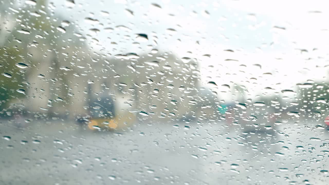 방울에 차의 앞 유리. 흐릿한 도시 거리와 자동차 교통.