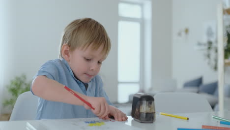 Ein-4-jähriger-Junge-Sitzt-Zu-Hause-Am-Tisch-Im-Wohnzimmer-Und-Zeichnet-Mit-Farbstiften-Auf-Papier