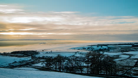 Inversión-De-Nubes-Que-Cubre-El-Valle-Del-Edén-En-Cumbria-Con-Las-Montañas-Lakeland-Al-Fondo,-Y-El-Sol-Atravesando-Las-Nubes-E-Iluminando-Los-árboles-En-Primer-Plano