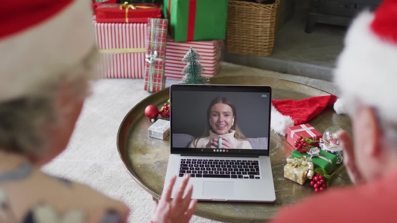 pareja caucásica de alto nivel usando un portátil para una videollamada de navidad con una mujer feliz en la pantalla