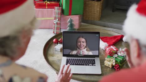 Pareja-Caucásica-Mayor-Usando-Una-Computadora-Portátil-Para-Una-Videollamada-Navideña-Con-Una-Mujer-Feliz-En-La-Pantalla