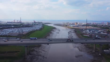 Rising-drone-shot-over-River-Avon-in-Bristol-looking-over-busy-M5-Motorway-bridge-with-Avonmouth-docks-and-bristol-channel-in-the-distance