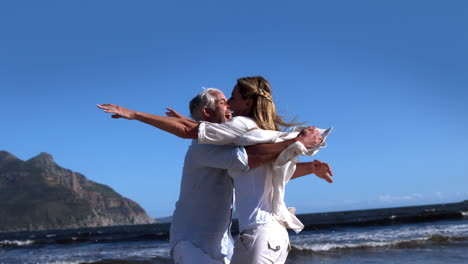 una pareja despreocupada corriendo y abrazándose en la playa.