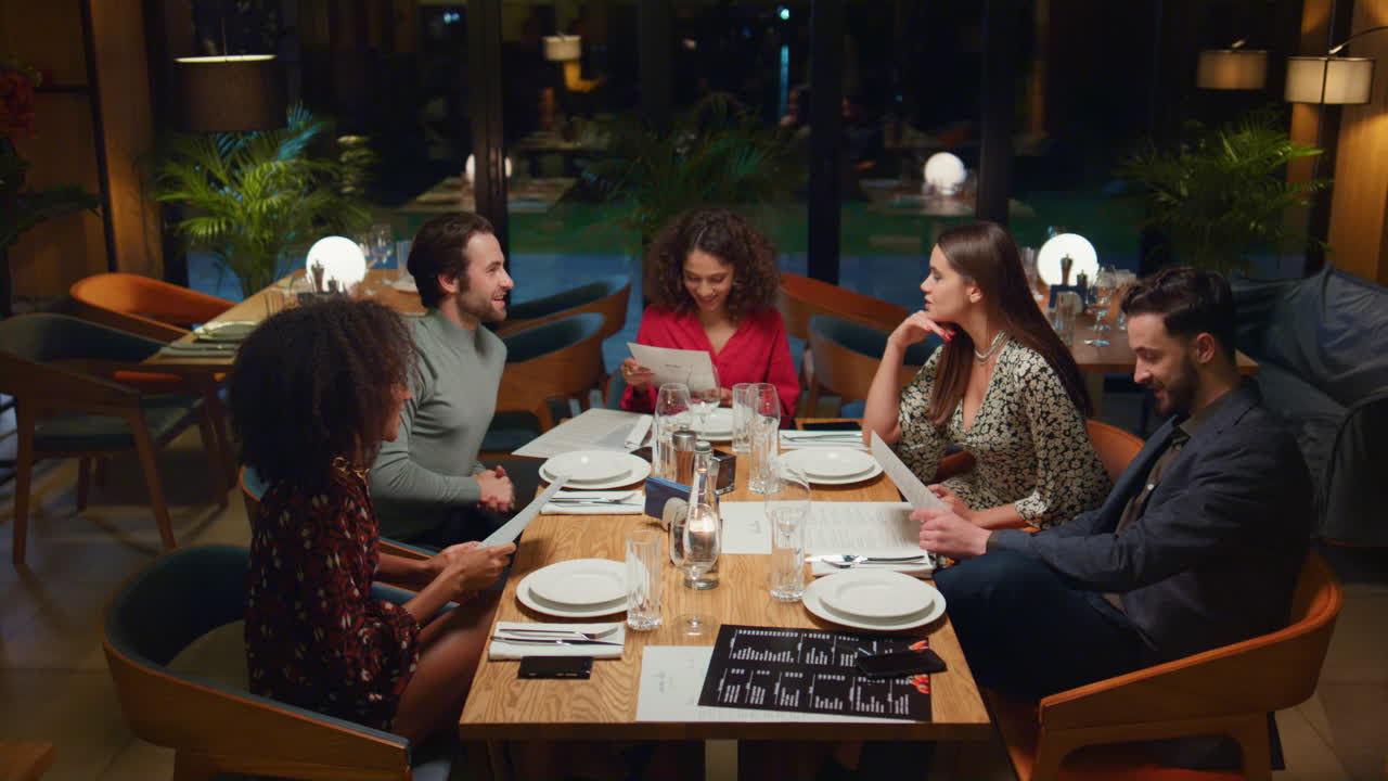 Mixed race friends talking in restaurant. People group choosing menu in cafe.