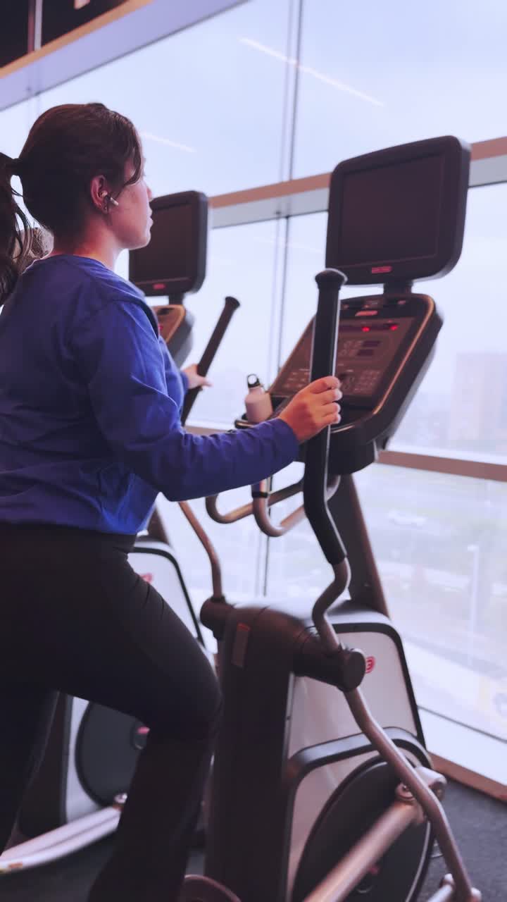 Young woman working out on elliptical trainer in gym