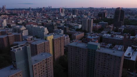 aerial footage smoothly rolls down from sunrise skyline of harlem nyc down to the tops of housing project rooftops