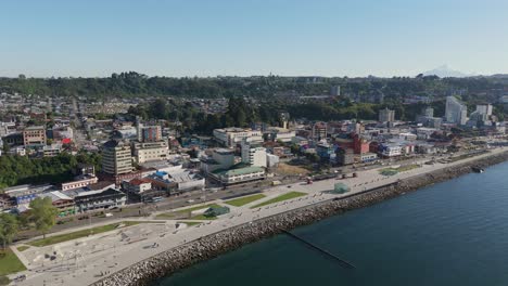 drone capturing the coastal cityscape of puerto montt, showcasing the diego portales waterfront, buildings, and green hills, in los lagos region, chile