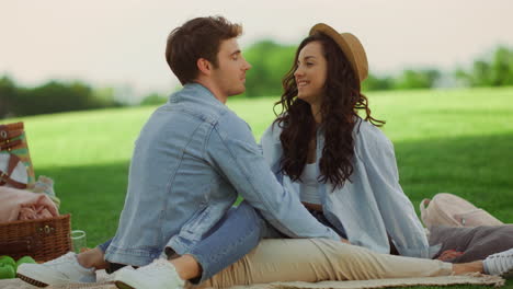 loving couple spending time on picnic. girl and guy sitting on blanket in park