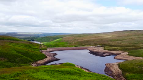 aerial view rotating across peaceful untouched marsden moorland valley lagoon in peak district countryside