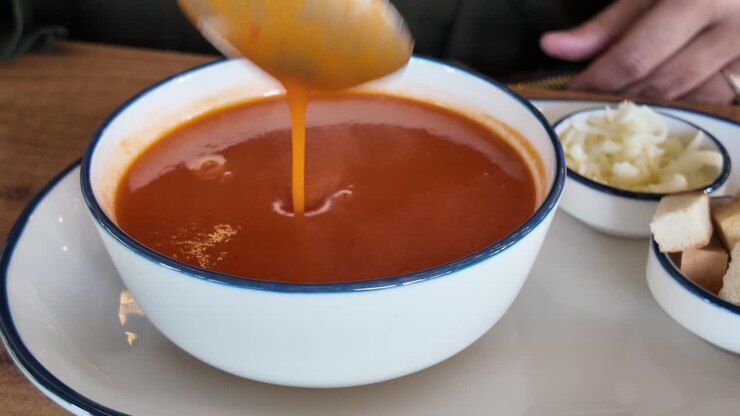 Persona che mangia zuppa di pomodoro