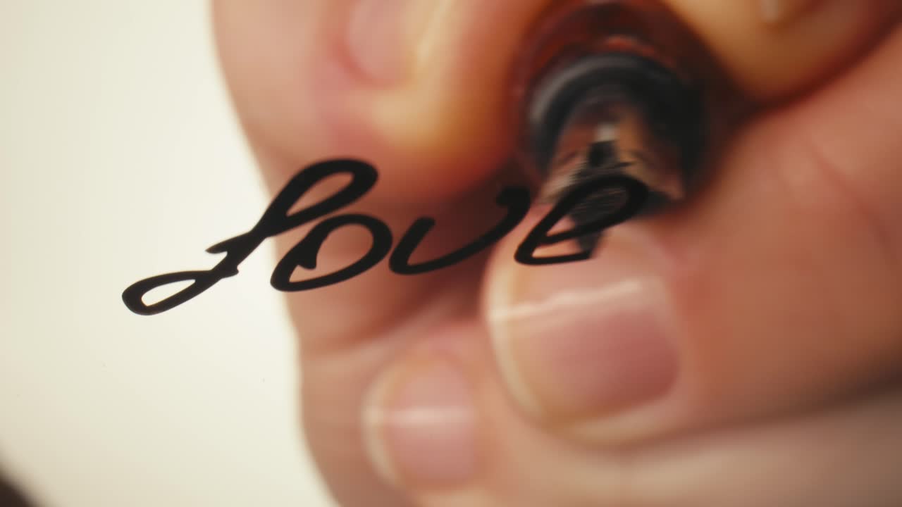 Close-up of a Hand Writing the Word 'Love' with a Fountain Pen