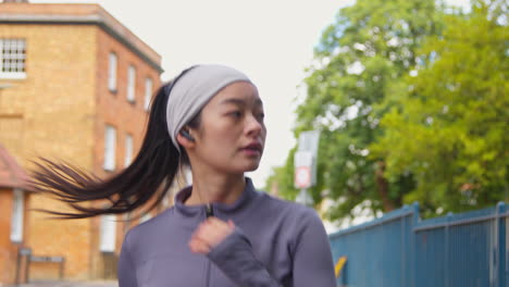 Close-Up-Of-Young-Woman-Exercising-Running-Along-Urban-Street-Wearing-Wireless-Earbuds-2