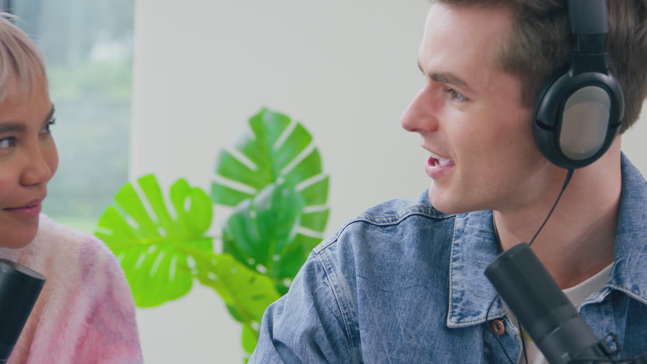 pareja con auriculares haciendo vlogs con micrófono transmitiendo en vivo riendo y hablando