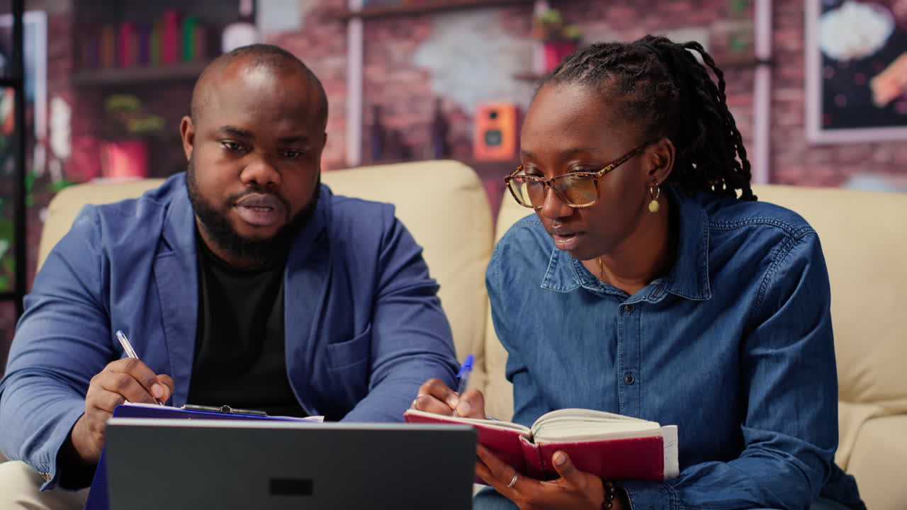 Black man and woman writing a report with information from notebook