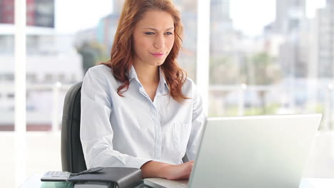 happy businesswoman sitting while using a laptop