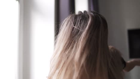 cheerful woman dances against the background of the large windows of her apartment in the morning