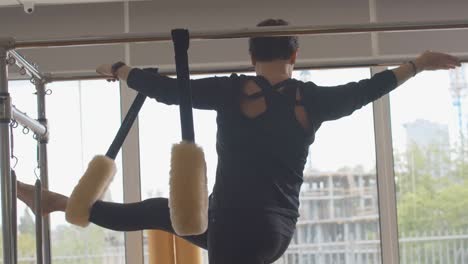 live camera moving down as senior woman training on exercise bench. back view of confident senior caucasian sportswoman standing with one leg in pilates loop and bending