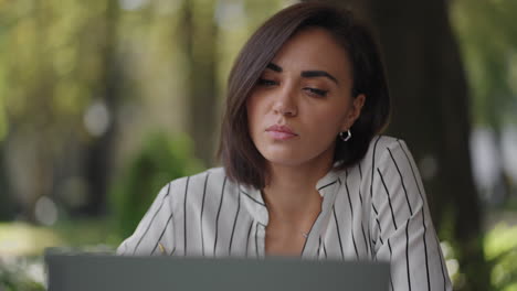 mujer serio talentosa morena árabe grupo étnico hispano se sienta en una mesa en un café de verano con una computadora portátil. considera resolver problemas. mujer de negocios desconcertada. retrato de una hermosa mujer de negocios